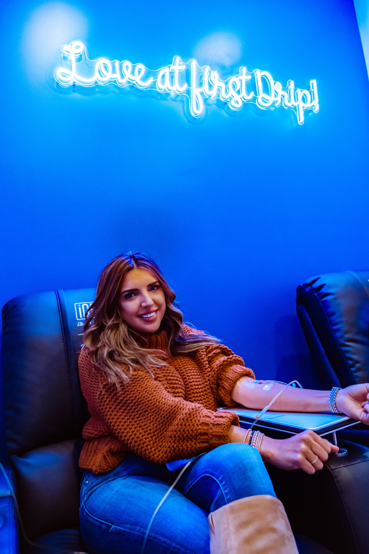 iCRYO SouthPark guest receiving an IV drip under the Love at First Drip neon